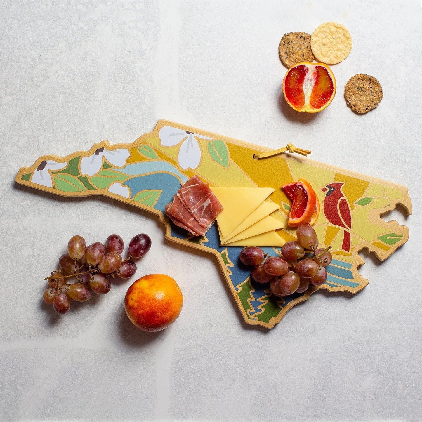 North Carolina State Shaped Cutting Board, Summer Stokes Art | State charcuterie board with colorful hand-drawn landscape art. Smooth reverse side for food prep. Hang tie for wall display. - Colors A