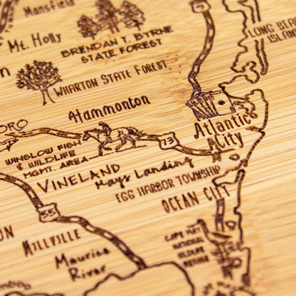 A Slice of Life New Jersey Engraved Map Cutting Board | 11” x 8.75” charcuterie board with engraved state map artwork. Smooth reverse side for food prep. Hang tie for wall display. - Colors A