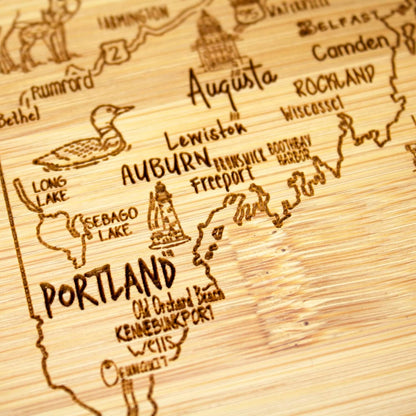 A Slice of Life New Jersey Engraved Map Cutting Board | 11” x 8.75” charcuterie board with engraved state map artwork. Smooth reverse side for food prep. Hang tie for wall display. - Colors A