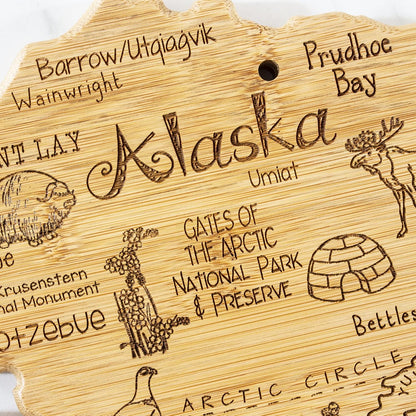 Destination Alaska State Shaped Cutting Board | State charcuterie serving board with engraved map artwork. Smooth reverse side for food prep. Hang tie for wall display.