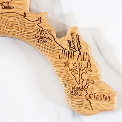 Destination Alaska State Shaped Cutting Board | State charcuterie serving board with engraved map artwork. Smooth reverse side for food prep. Hang tie for wall display.